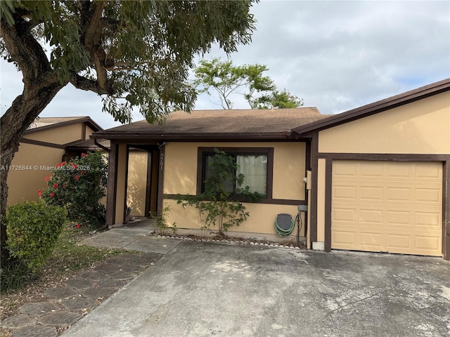 single story home with a garage, concrete driveway, and stucco siding