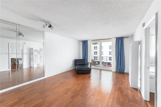 unfurnished room featuring baseboards, a textured ceiling, and wood finished floors