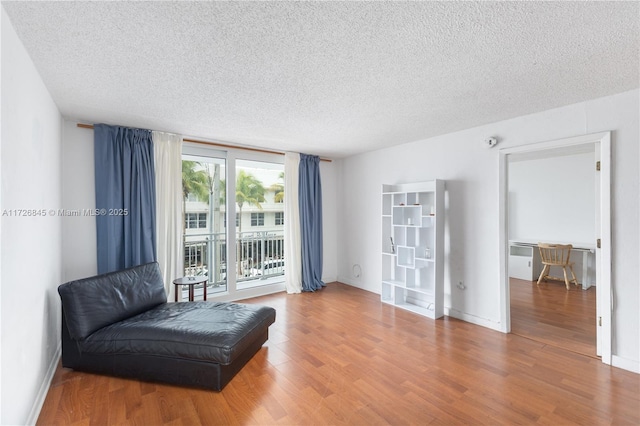 living area featuring baseboards, a textured ceiling, and wood finished floors