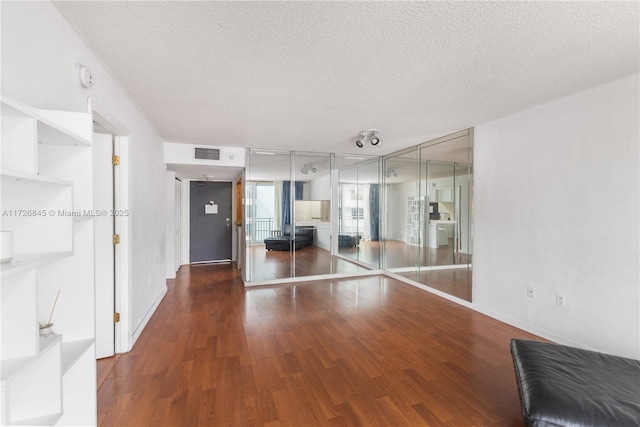 living room featuring a textured ceiling, visible vents, and wood finished floors