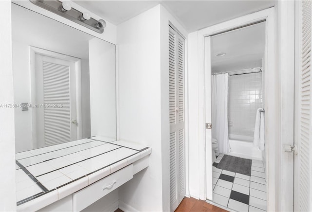 full bath featuring a closet, shower / bath combination with curtain, and toilet