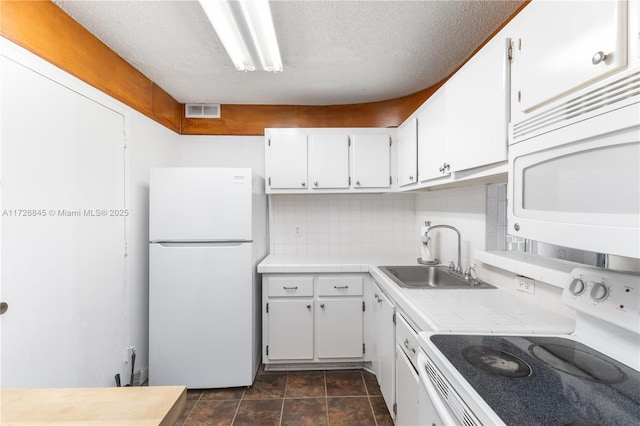 kitchen with tile counters, a sink, white cabinets, and white appliances