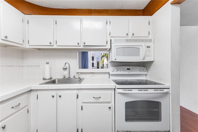 kitchen with white appliances, white cabinetry, a sink, and backsplash