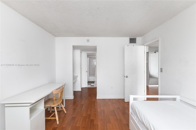 bedroom featuring a textured ceiling, visible vents, built in desk, wood finished floors, and baseboards