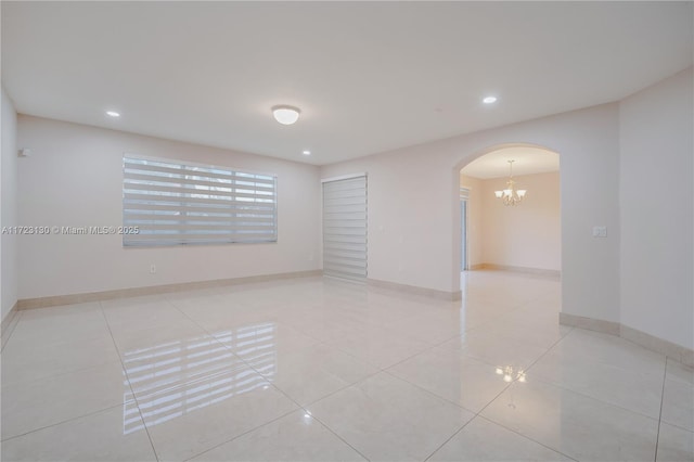 spare room featuring light tile patterned floors and a chandelier