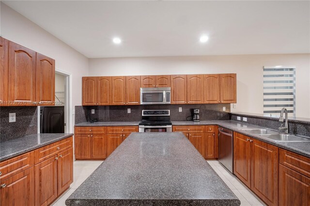 kitchen with sink, tasteful backsplash, light tile patterned floors, a kitchen island, and stainless steel appliances