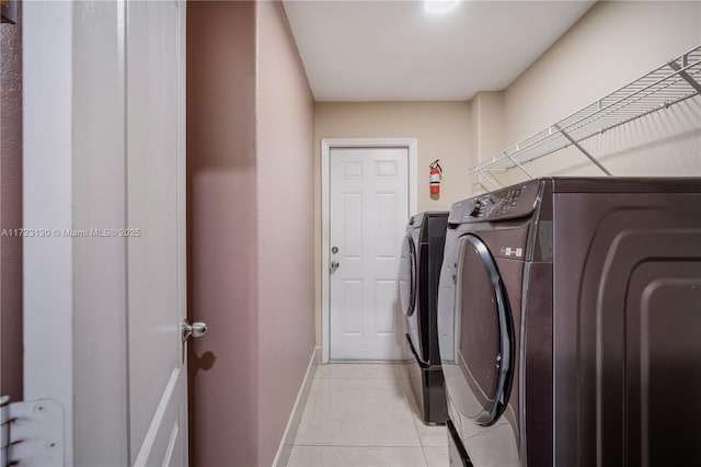 laundry area with separate washer and dryer and light tile patterned floors