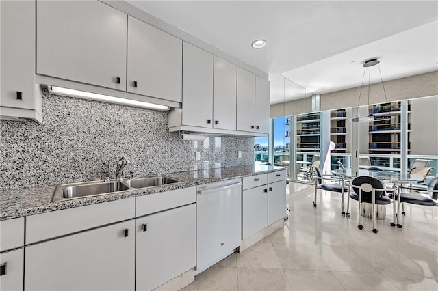 kitchen featuring sink, white dishwasher, light stone counters, tasteful backsplash, and white cabinets