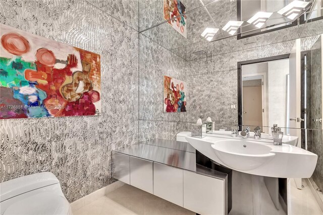 bathroom with toilet, tile patterned flooring, and tile walls