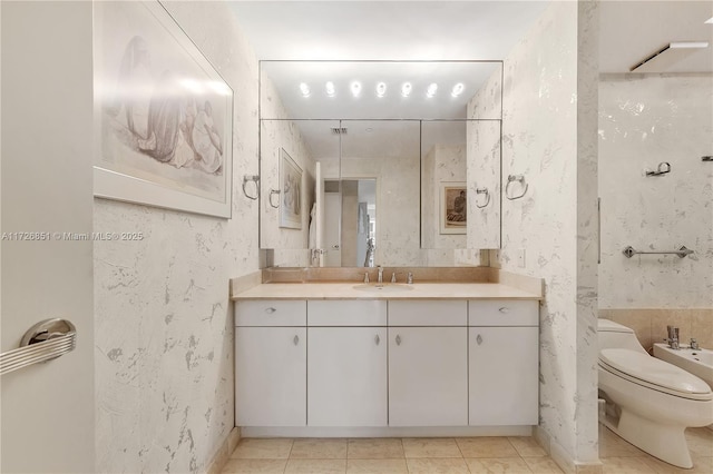 bathroom with a bidet, vanity, tile patterned floors, and toilet