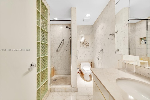 bathroom featuring tile patterned flooring, tile walls, a tile shower, vanity, and toilet