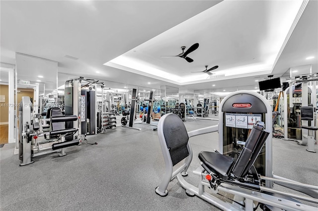 exercise room with a raised ceiling and ceiling fan