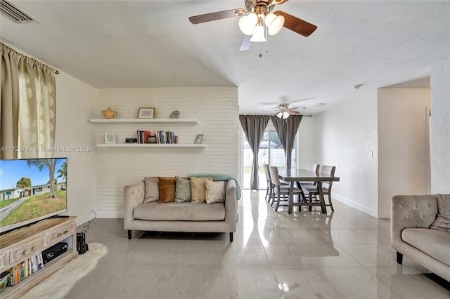 living room featuring ceiling fan and brick wall