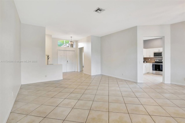 tiled empty room with an inviting chandelier