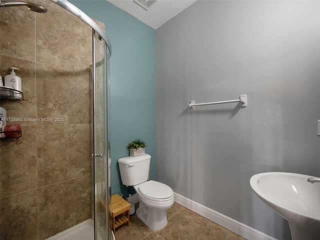 bathroom featuring toilet, a textured ceiling, tile patterned floors, a shower with shower door, and sink