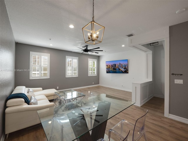 living room featuring ceiling fan with notable chandelier, a textured ceiling, and hardwood / wood-style flooring