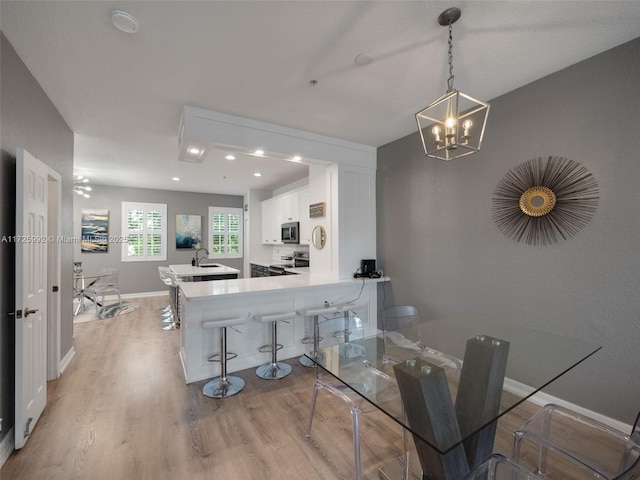 dining room with sink, light hardwood / wood-style flooring, and an inviting chandelier