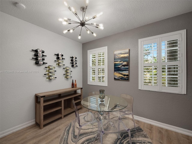 dining space with a chandelier, hardwood / wood-style floors, and a textured ceiling