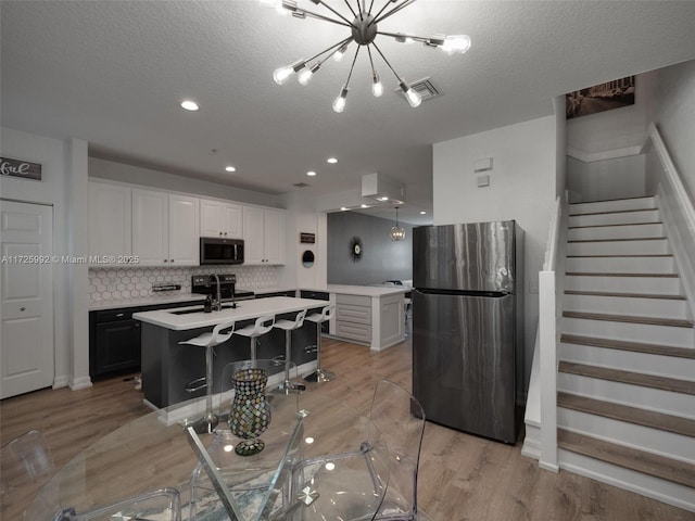 kitchen with a kitchen island with sink, appliances with stainless steel finishes, decorative backsplash, sink, and white cabinetry