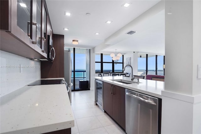 kitchen featuring wine cooler, sink, an inviting chandelier, stainless steel appliances, and a water view