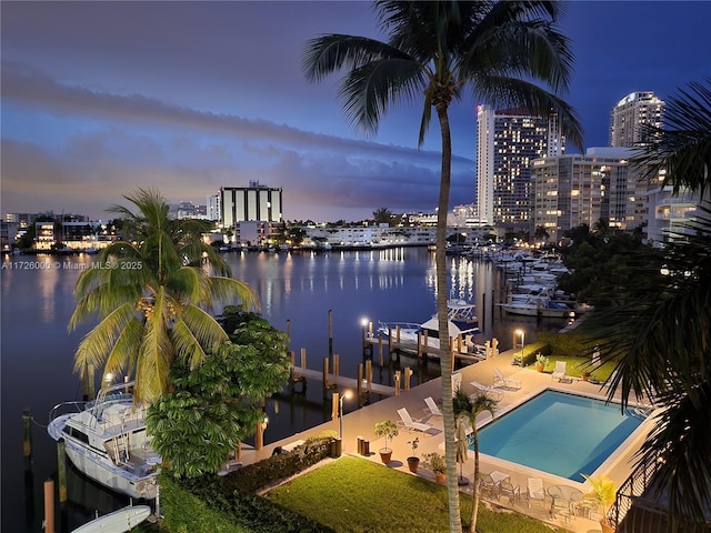 view of dock featuring a water view, a patio area, and a community pool