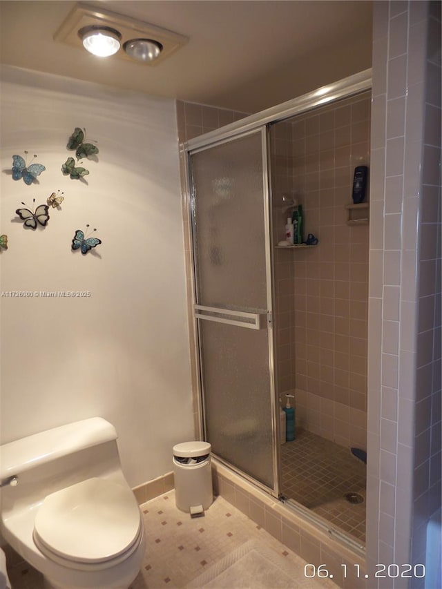 bathroom featuring toilet, tile patterned flooring, and walk in shower