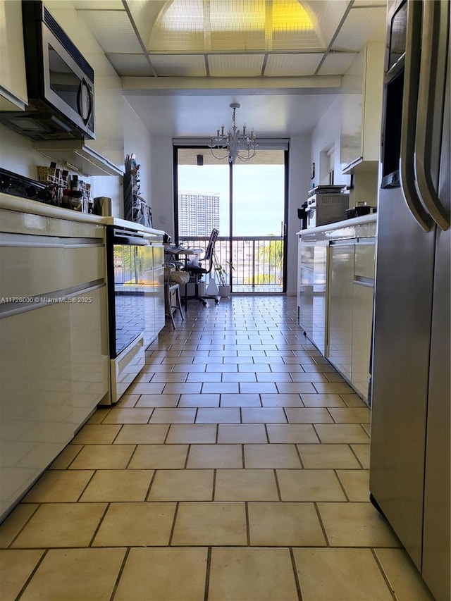 kitchen with a notable chandelier, pendant lighting, expansive windows, stainless steel appliances, and white cabinets