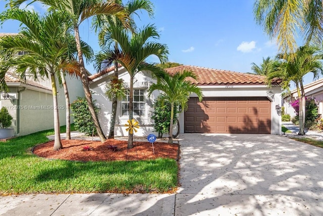 mediterranean / spanish-style house with a garage, driveway, a tiled roof, and stucco siding