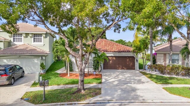 mediterranean / spanish-style home with a tiled roof, concrete driveway, stucco siding, and a front yard