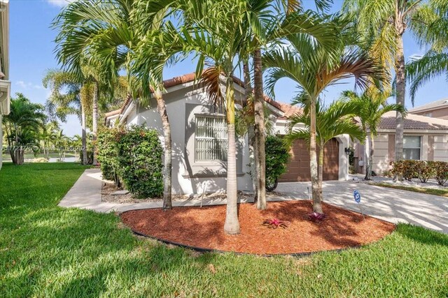 exterior space featuring driveway, stucco siding, and a front lawn