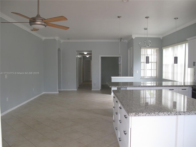 kitchen with pendant lighting, white cabinets, a kitchen island, ceiling fan, and light stone counters