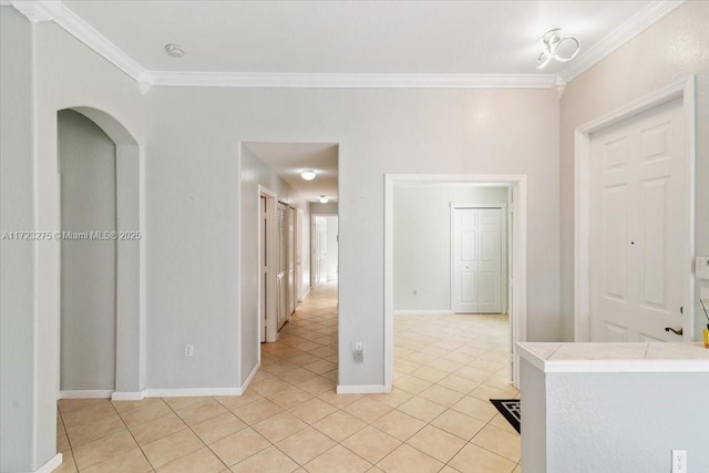 empty room with crown molding, light tile patterned floors, and baseboards