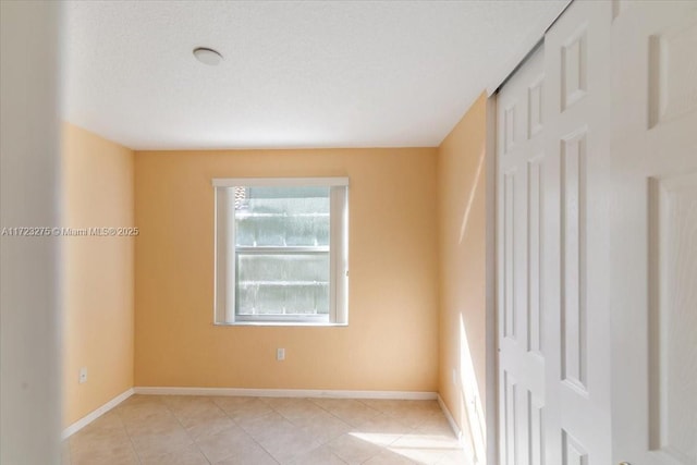 empty room with light tile patterned floors and baseboards