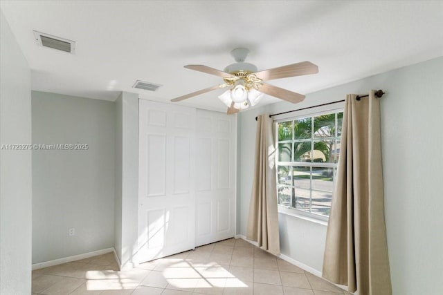 empty room featuring light tile patterned floors, baseboards, a ceiling fan, and visible vents