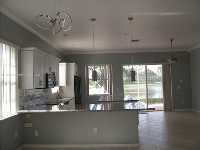 kitchen with kitchen peninsula, light tile patterned floors, hanging light fixtures, white cabinets, and light stone counters