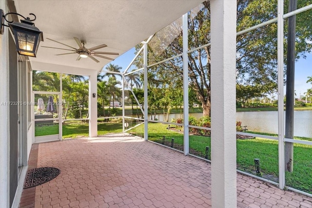 unfurnished sunroom with ceiling fan and a water view