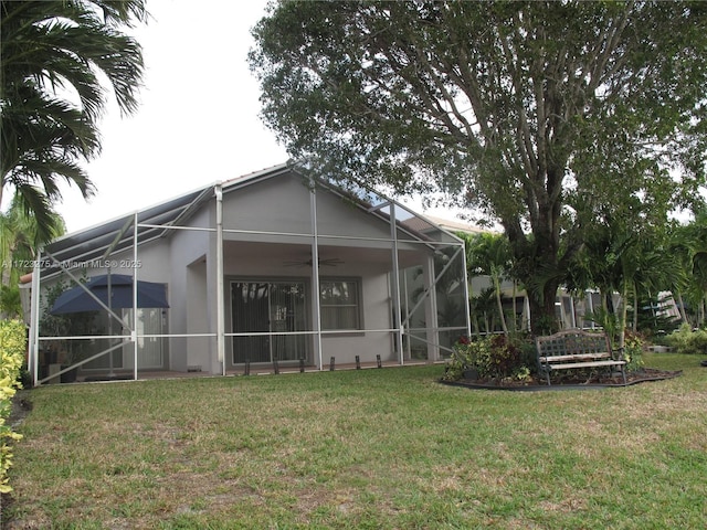 back of property featuring ceiling fan and a yard