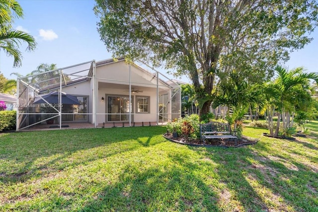 rear view of property featuring a yard, a ceiling fan, and a lanai
