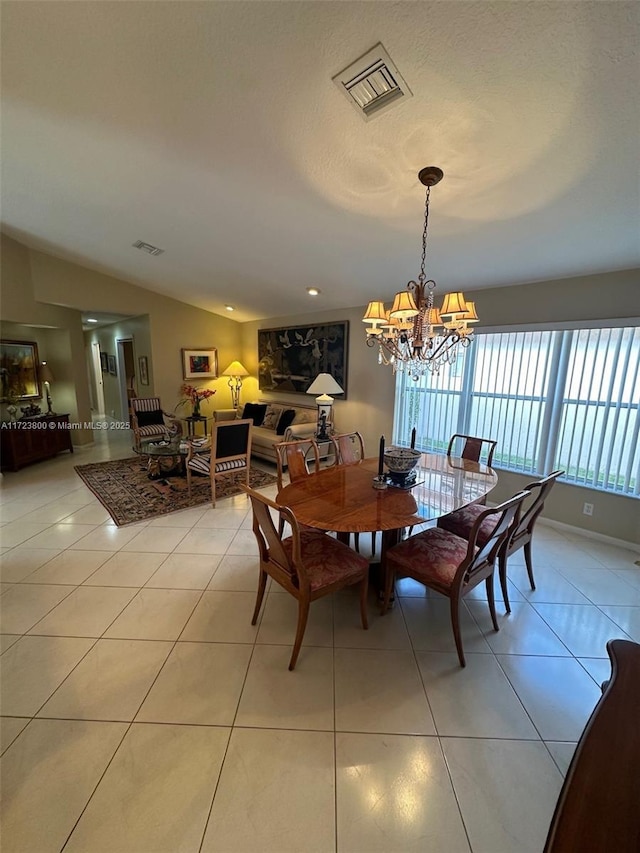 tiled dining room with an inviting chandelier and vaulted ceiling