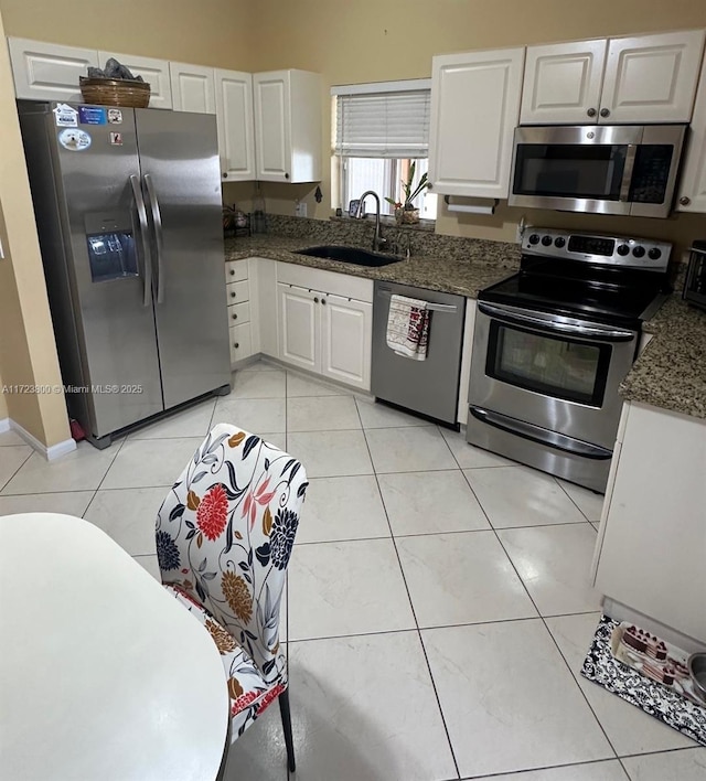 kitchen with light tile patterned flooring, appliances with stainless steel finishes, white cabinetry, and sink