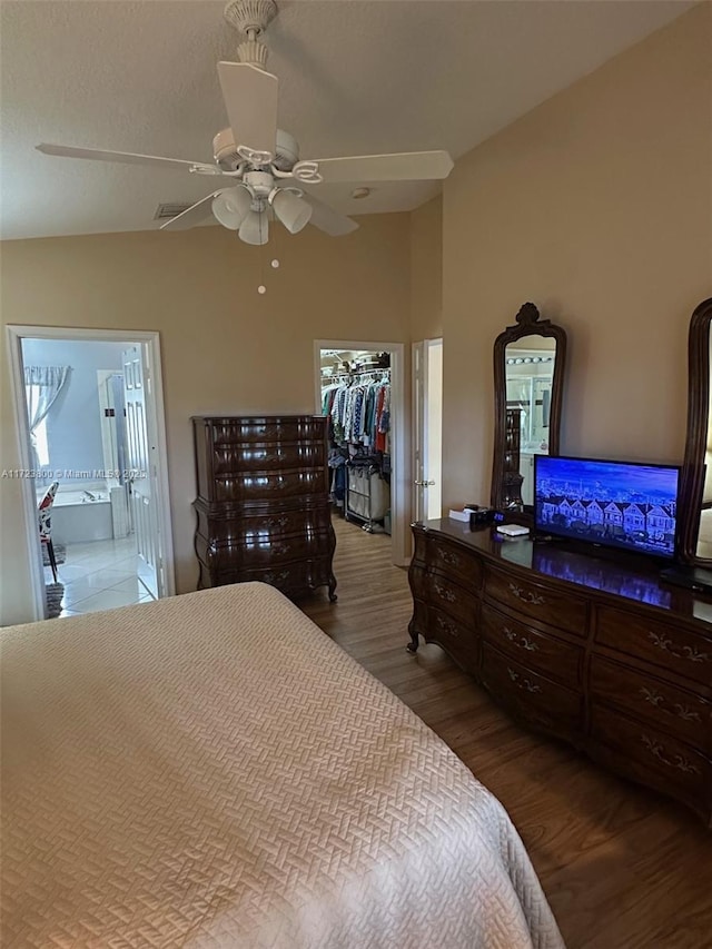 bedroom with ceiling fan, hardwood / wood-style flooring, connected bathroom, a walk in closet, and a closet