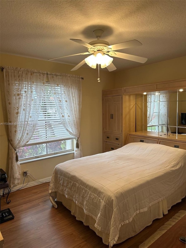 bedroom featuring ceiling fan, hardwood / wood-style floors, and a textured ceiling