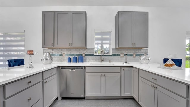 kitchen with stainless steel dishwasher, backsplash, sink, and gray cabinets