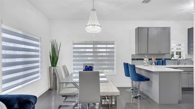 tiled dining space with sink and a notable chandelier