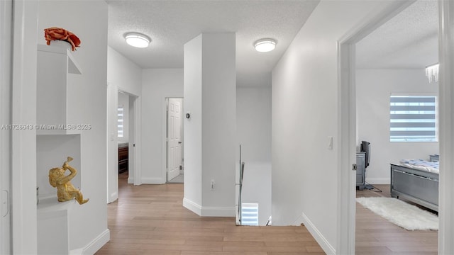 hall featuring a textured ceiling and light hardwood / wood-style floors