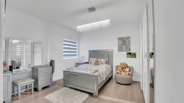 bedroom featuring light hardwood / wood-style floors, a chandelier, and a textured ceiling