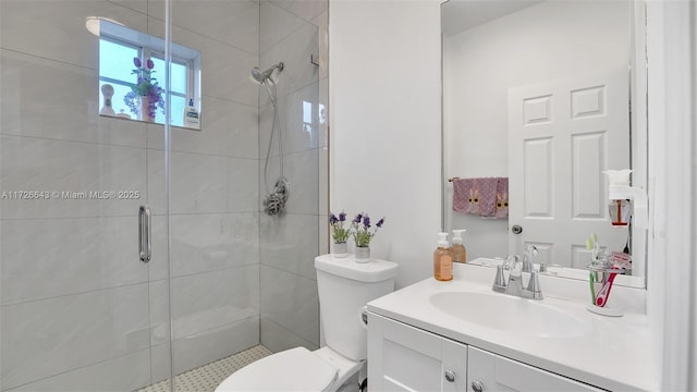 bathroom featuring a shower with door, toilet, and vanity