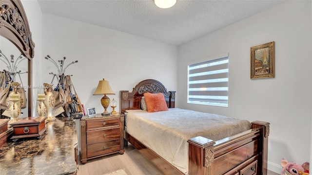 bedroom with a textured ceiling and light wood-type flooring