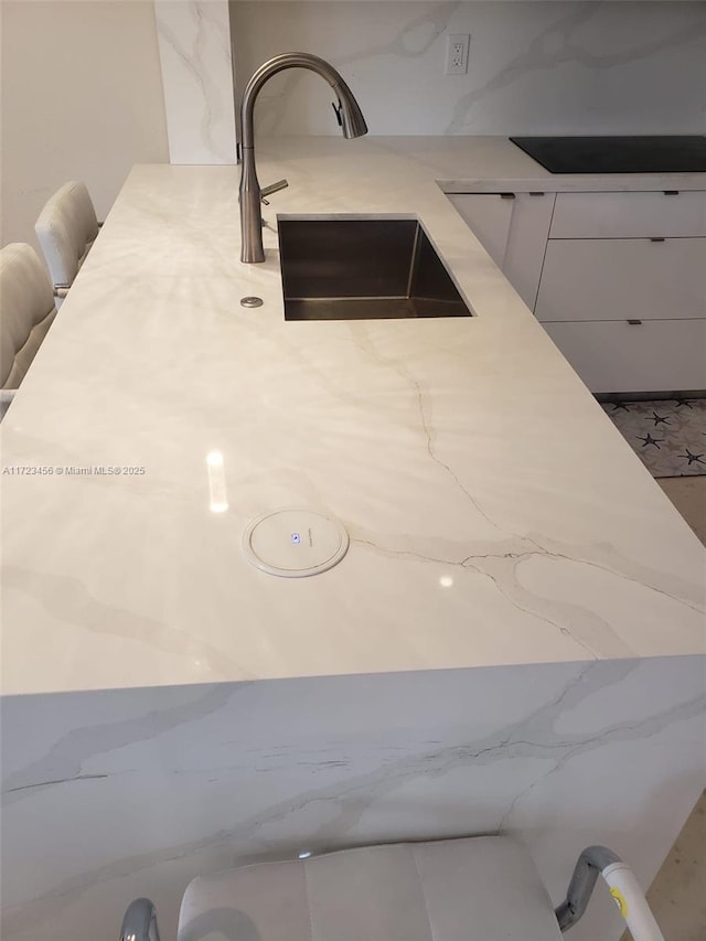 room details featuring white cabinets, sink, and black electric cooktop