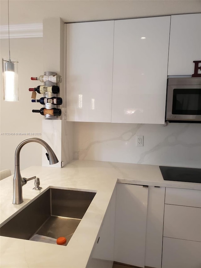 kitchen with pendant lighting, sink, white cabinetry, and decorative backsplash